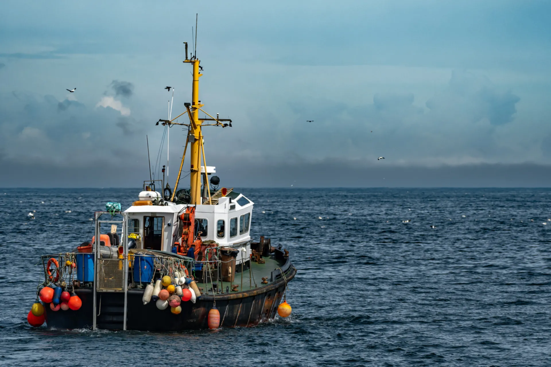 A fishing boat working on the open sea under a cloudy sky