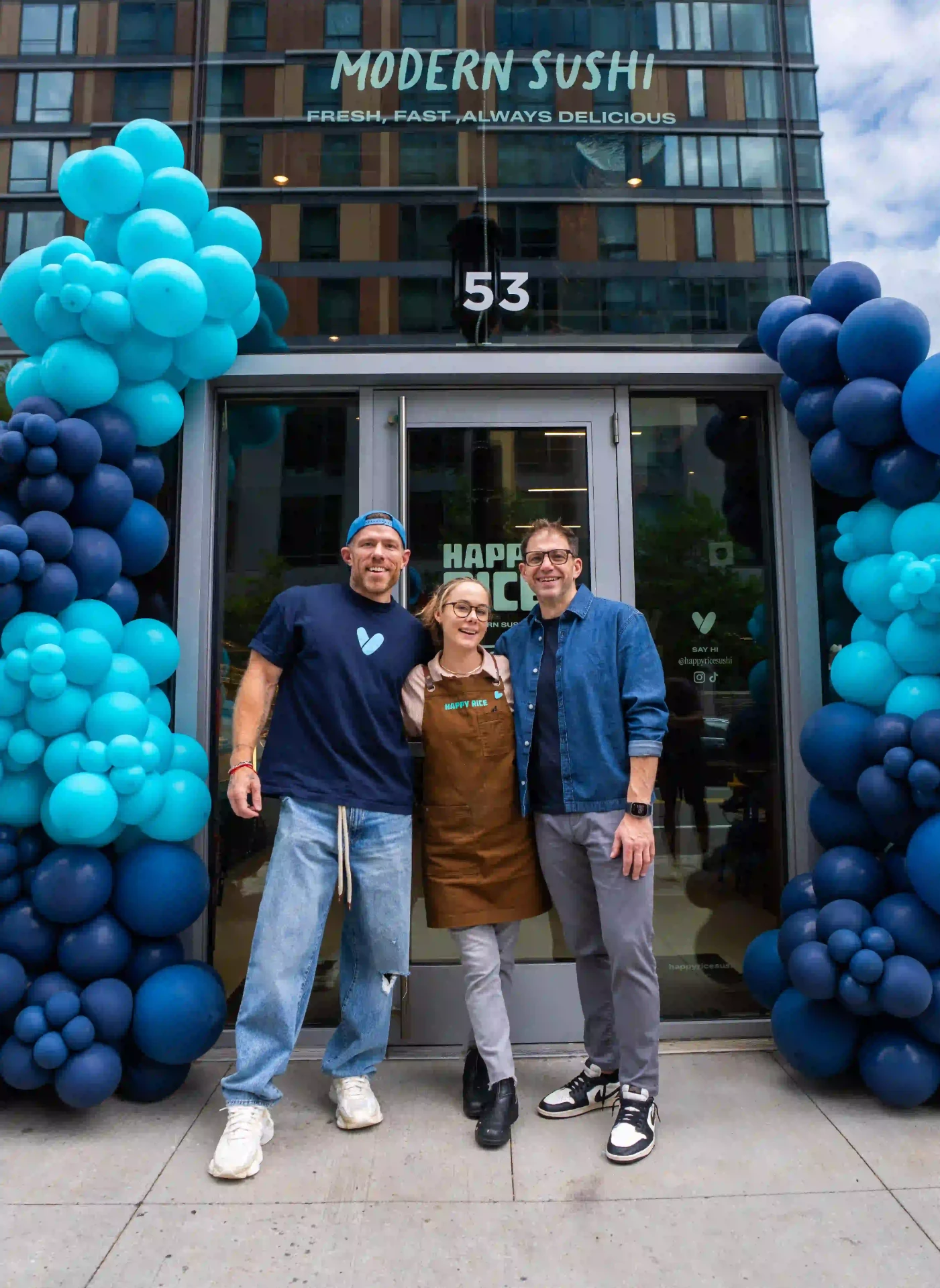 Happy Rice team standing outside the Boston shop entrance with blue balloon arches