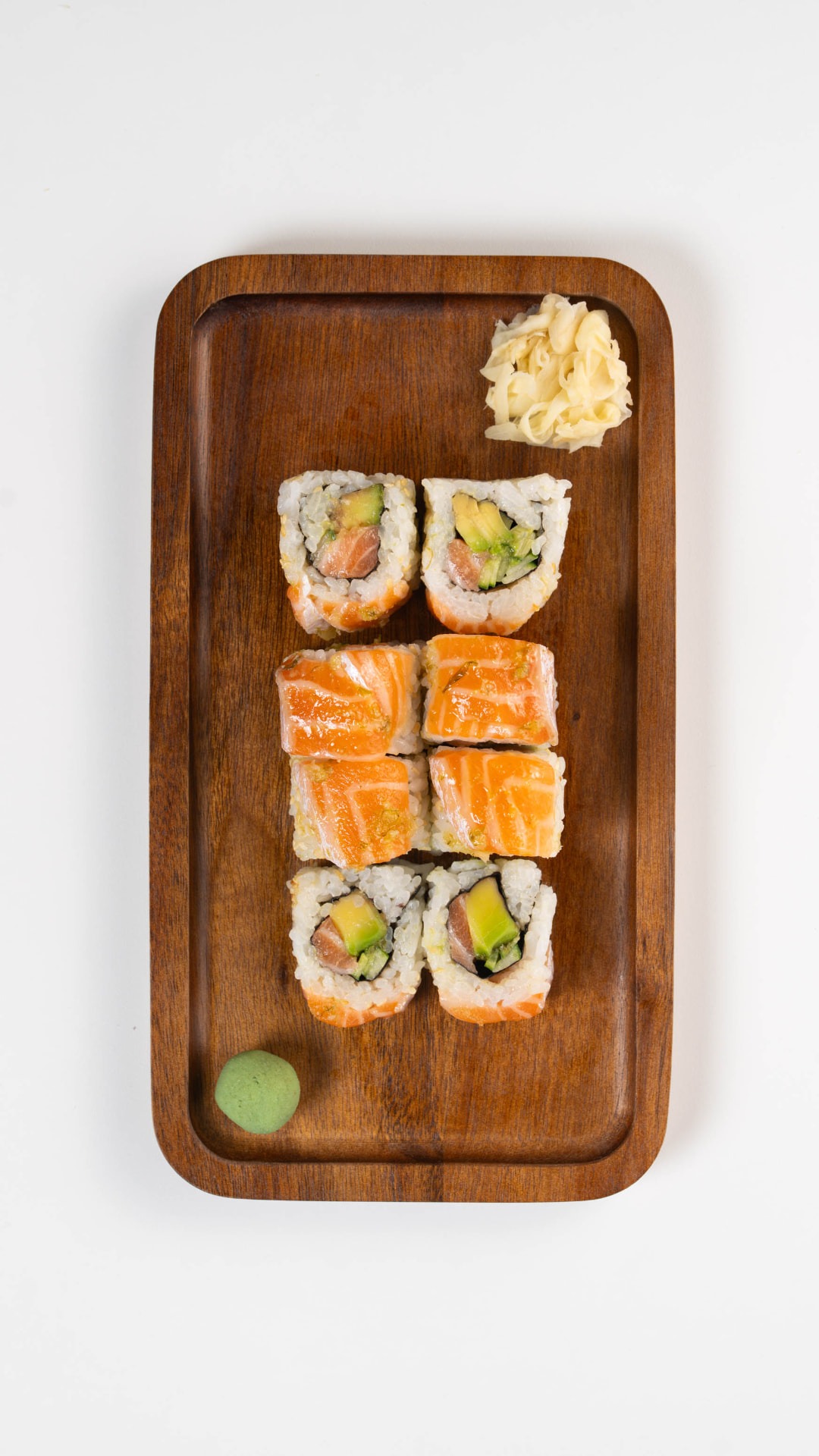 Salmon on Salmon Roll sliced on a wooden board with pickled ginger and wasabi