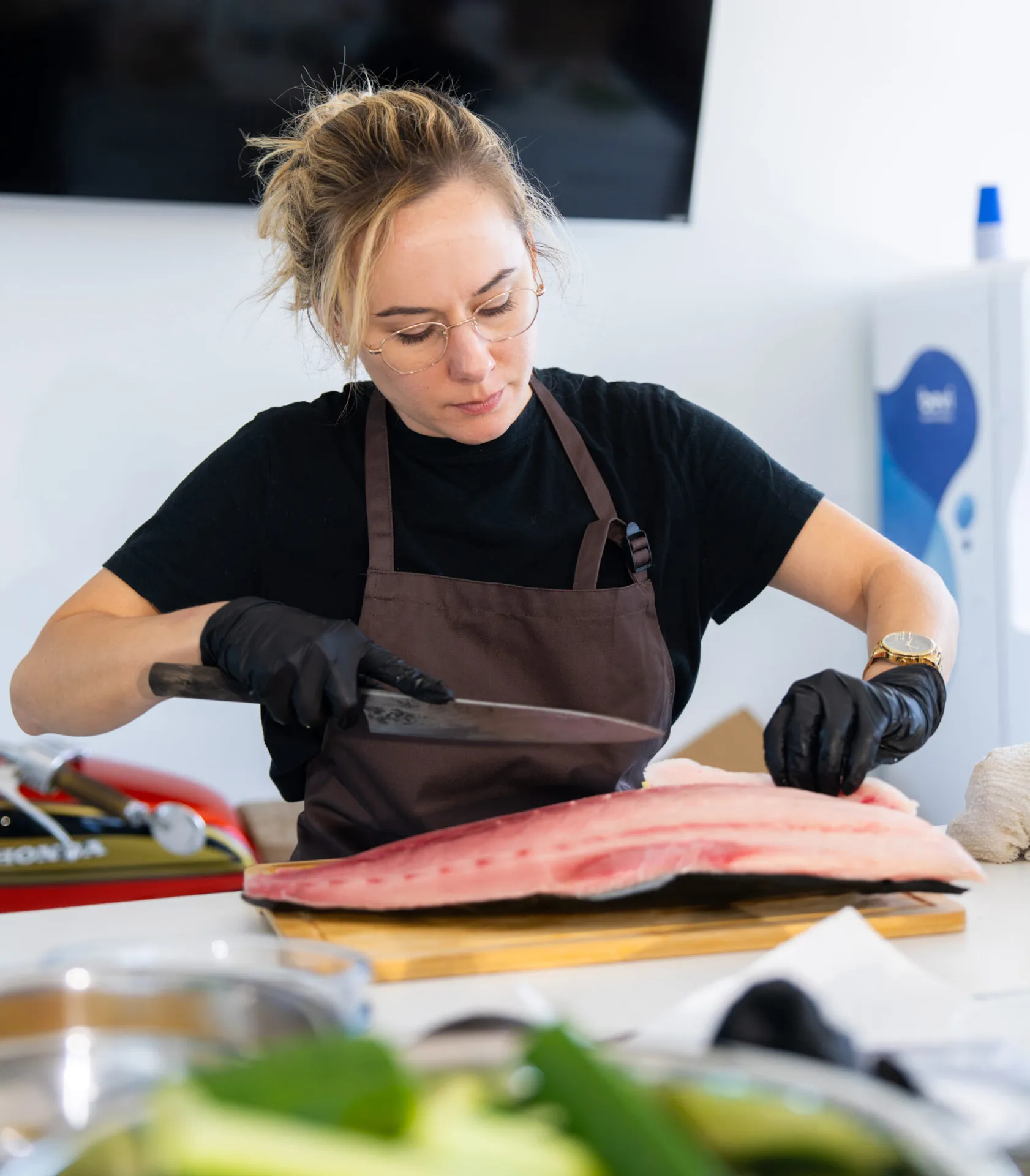 A Happy Rice chef slicing a fresh tuna loin on a wooden cutting board