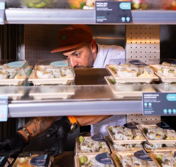 Happy Rice team member stocking fresh grab-and-go sushi in the Seaport restaurant