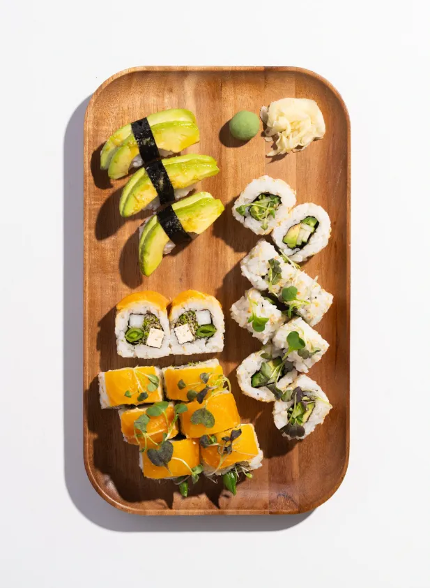 Green Machine Box with veggie rolls, plant protein rolls and avocado nigiri on a wooden tray