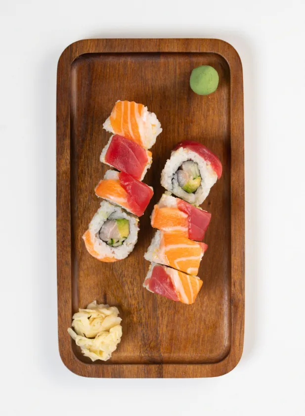 Three Sisters Roll with salmon, tuna and amberjack on a wooden board
