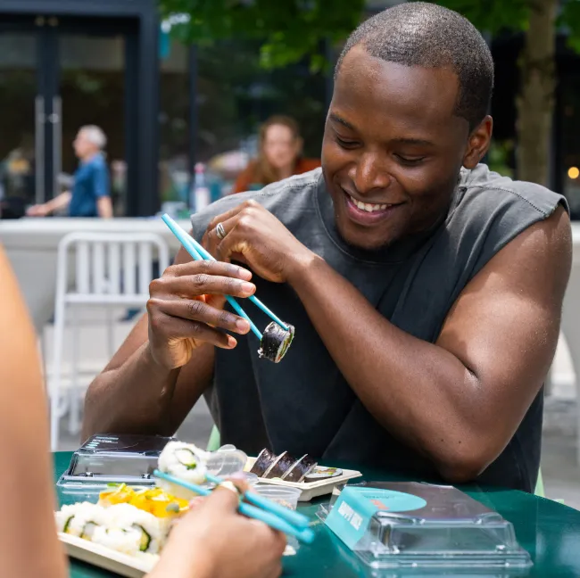 Man smiling while eating Happy Rice sushi outdoors