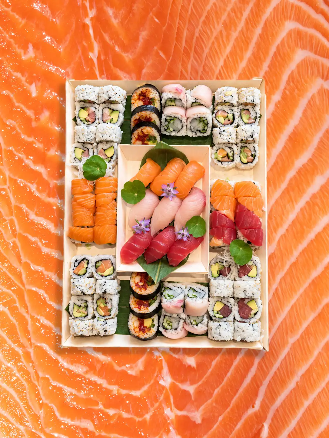 Happy Rice catering tray of assorted sushi rolls and nigiri on a salmon background